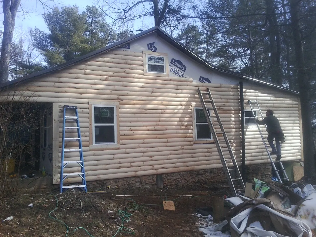Ladders set against fresh log siding during an exterior remodel in Bristol